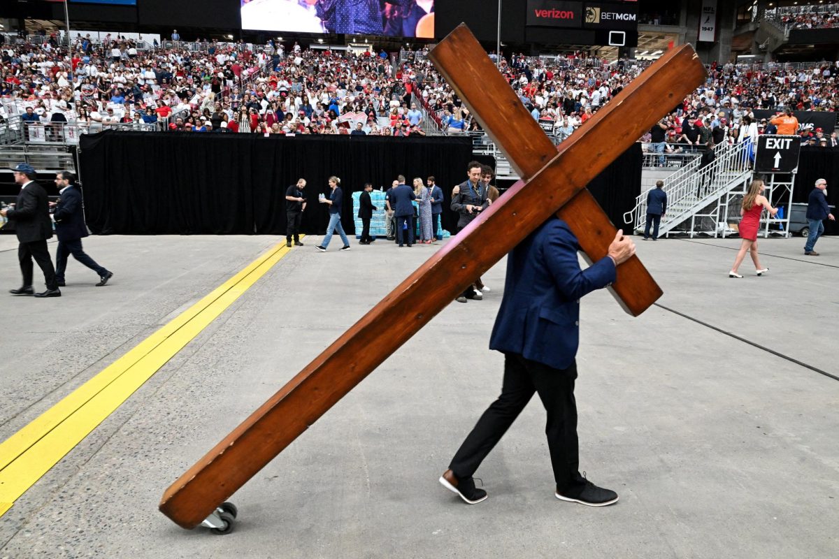 A person walks with a cross on the day a memorial service for slain conservative commentator Charlie Kirk at State Farm Stadium, in Glendale, Arizona, U.S., September 21, 2025. REUTERS/Caitlin O'Hara