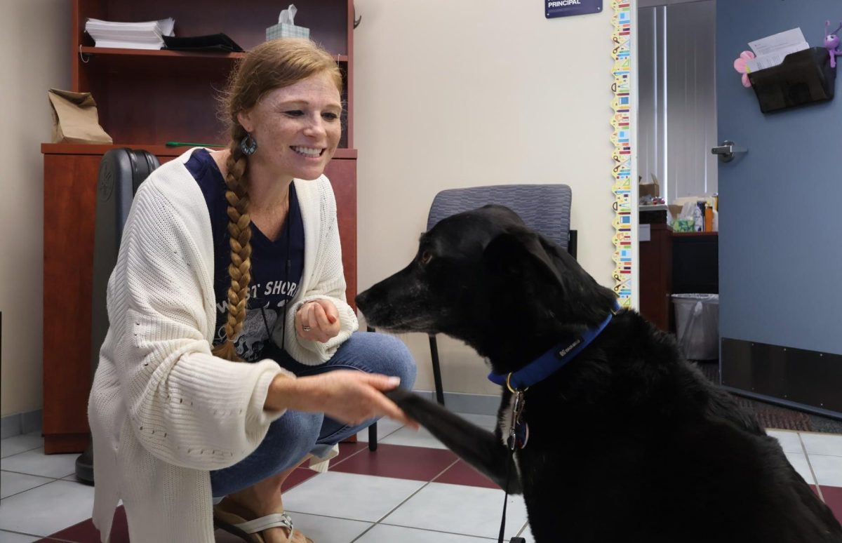 Meeting Tesla the therapy dog for the first time in Assistant Principal Sarah Perry’s office, science teacher Stefani Archibald greets her with a handshake and smile on Sept. 5.