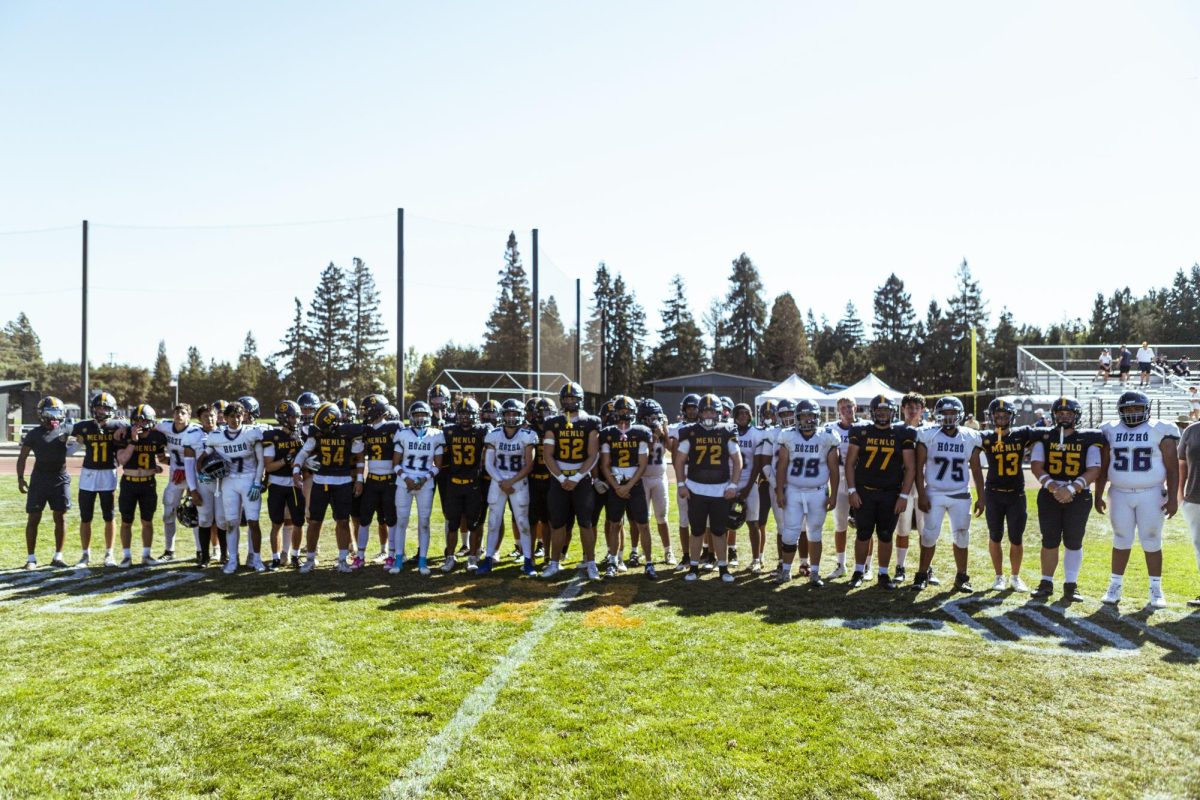 The Menlo and Hózhó football teams line up together after the game to take a photo.