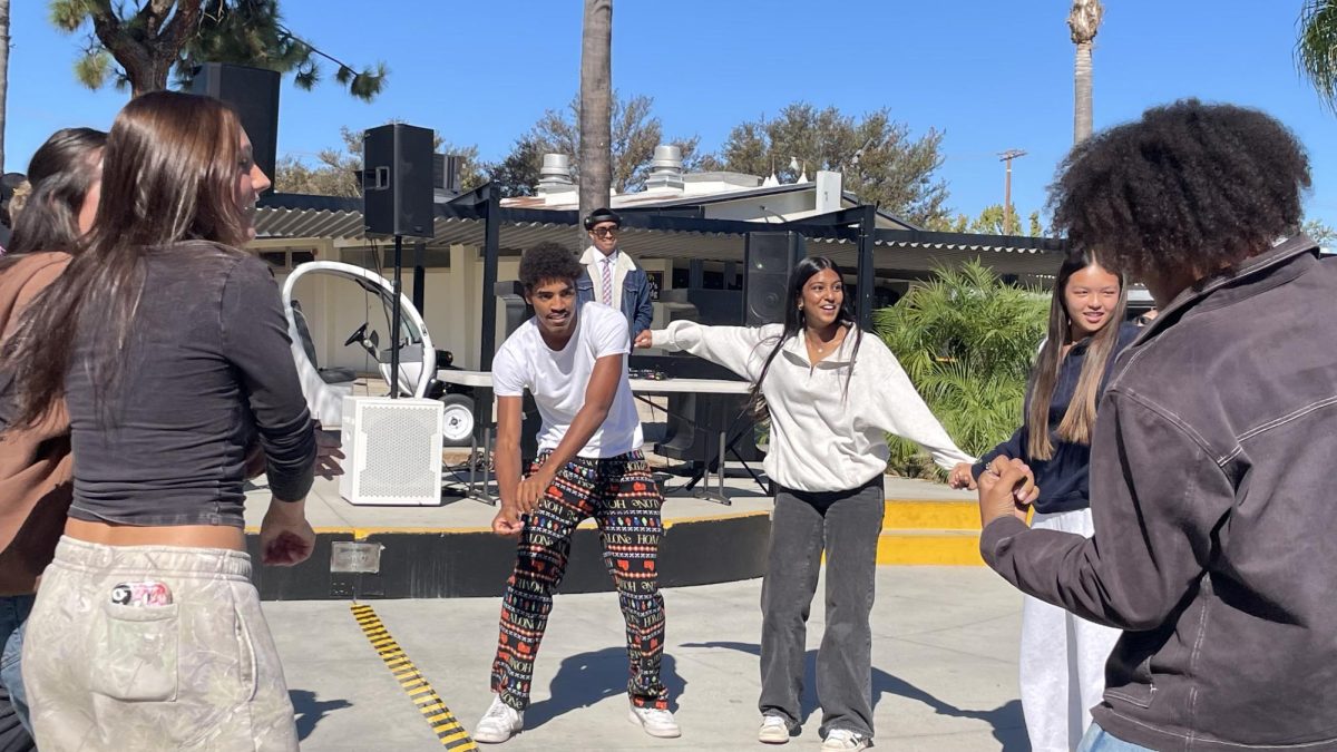 Cutline: Senior Pierrce Sandle (center) dances with other students in the quad during the DJ battle between social science teacher Marcus Reveles and athletic director Paul Jones on Thursday, October 16. 