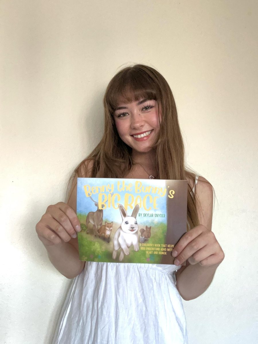 Skylar Snyder holds up her first published children's book that helps kids understand ADHD with empathy.