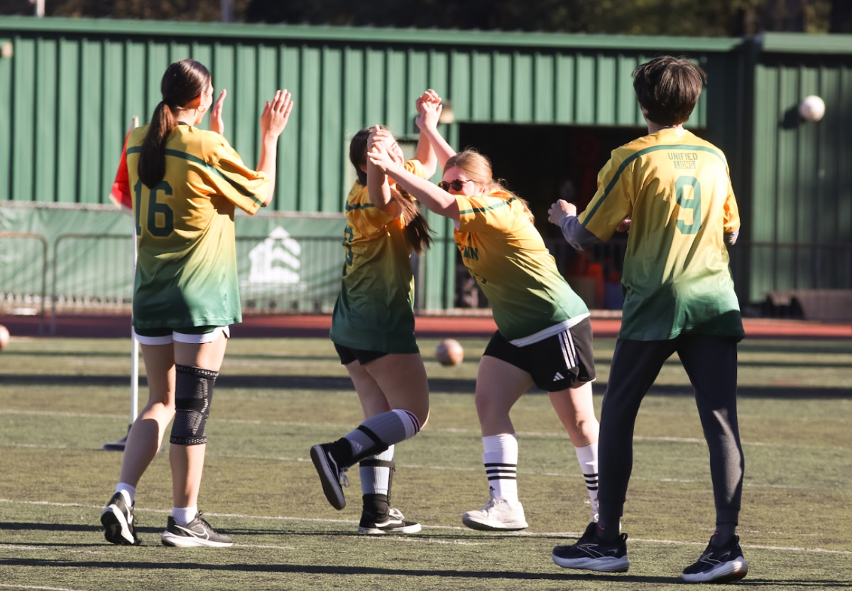 Unified soccer players Joanna Landazuri, junior, and Sophie Maher, senior, embrace one another with a high five after scoring a goal.