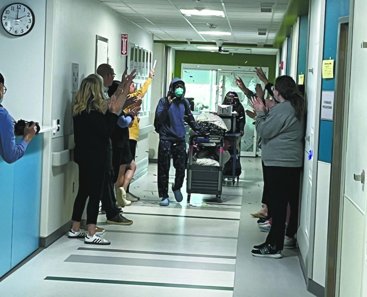 All done.  Former Bellevue East graduate, Martin Mwita Jr. walks through the hallway with nurses  after being discharged.  “I’d say trust the people and the process,” Mwita Jr. said. “The people that are with you during the process are professionals and it can be very easy to be skeptical, but I know they are here to help me.”