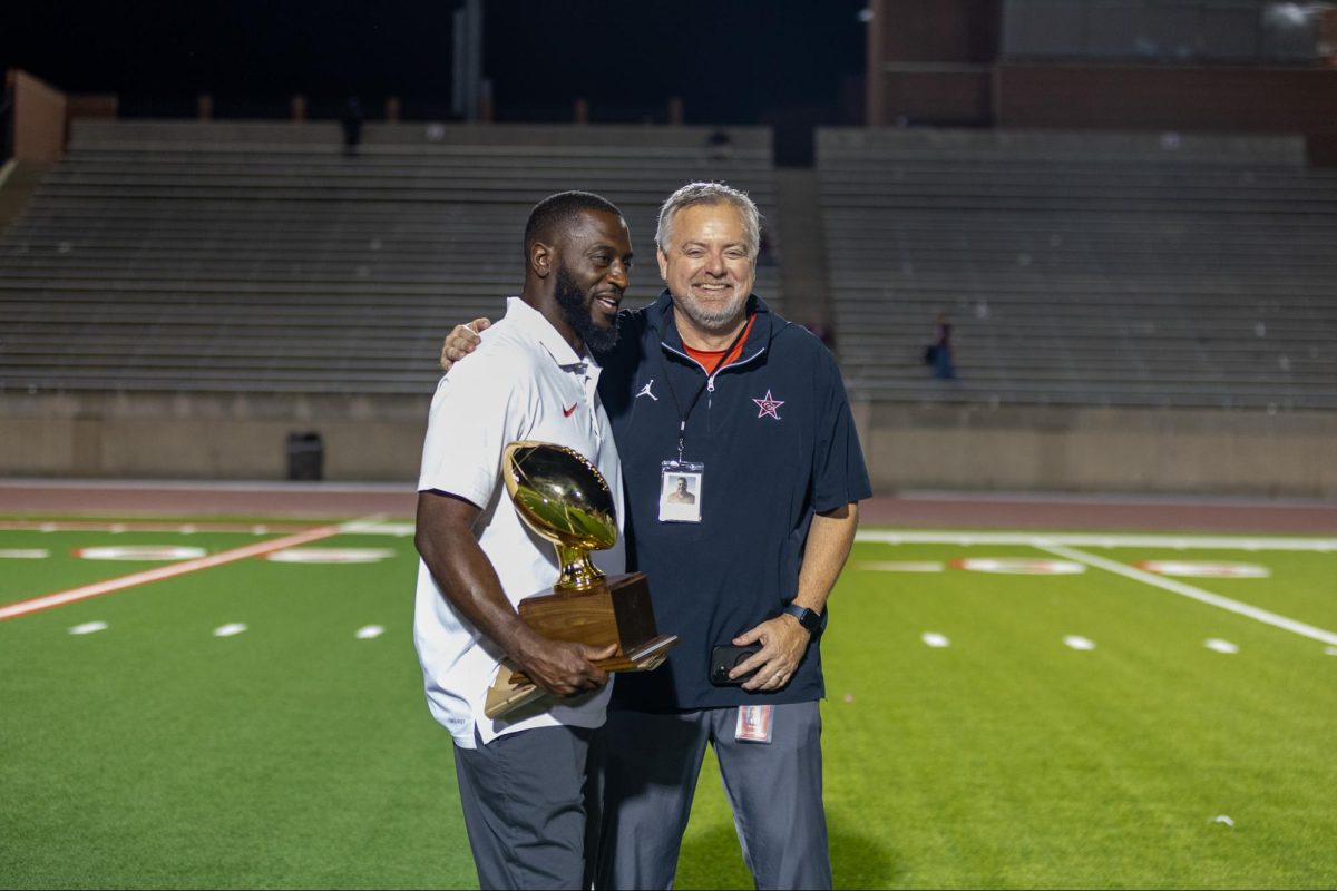 Coppell coach Anotnio Wiley, holding Class 6A area championship trophy with Coppell ISD athletics director Kit Pehl, is a highly-respected coach among the Texas high school football community. With openings at programs including Southlake Carroll and North Crowley, Wiley said he is happy in his current position at Coppell. Photo by Naila Ali