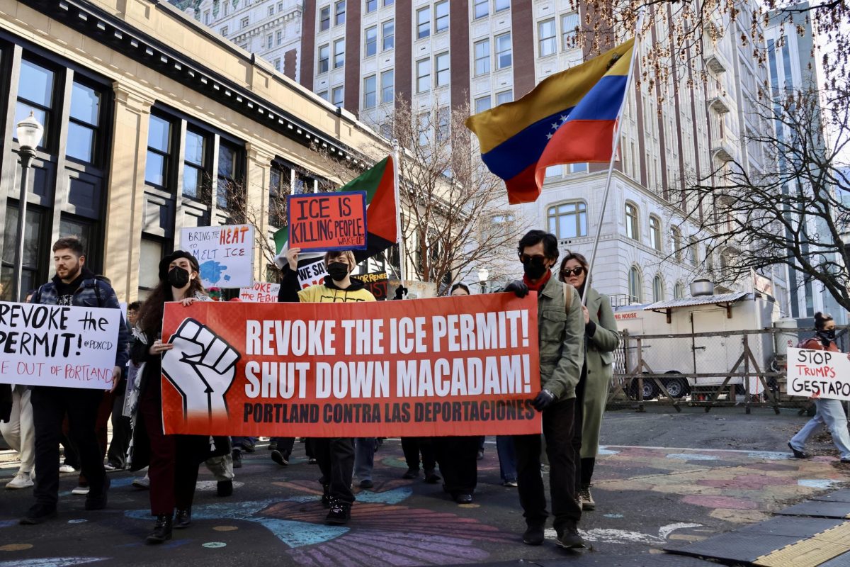 A large red banner reading out “REVOKE THE ICE PERMIT! SHUT DOWN MACADAM!” led the way as demonstrators walked through downtown Portland, a marching band following behind them.