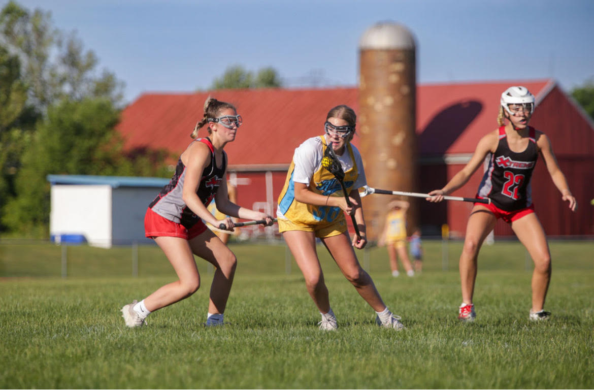 In yellow, Asha Parry ('28) cradles the lacrosse ball as she plays in a game. Parry plays right-side attack on several teams, although her nationally ranked team is called Alliance National. "Lacrosse has really taught me to stay grounded and just really cherish the moments I am having with my teammates," Parry said. "At the end of the day, that's what's going to matter rather than a specific outcome."
 (Photo courtesy of Asha Parry)