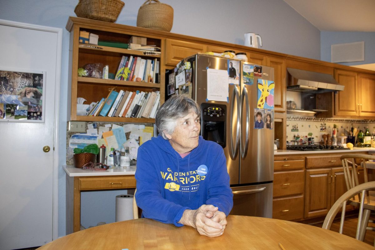 Anne Battle sits in her kitchen wearing an “I have Alzheimer’s” pin. The gift from her daughter, acting teacher Lisa Battle, is Anne’s latest attempt at breaking stigmas surrounding the neurological disorder. 