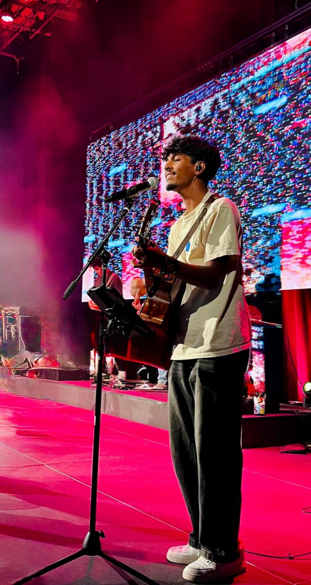 Junior, Vivin Goyal Undrajavapru, stands in front of his church crowd playing music on guitar. 